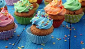 What Should I Bake at Home? Essential Tips and Suggestions for New Bakers Tasty cupcakes on wooden background. Birthday cupcake in rainbow colors